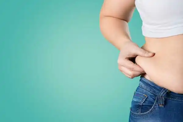 Image of woman pinching her love handles to show weight gain Colchester